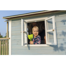 Kind im Fenster eines Holzspielhauses mit Fensterläden