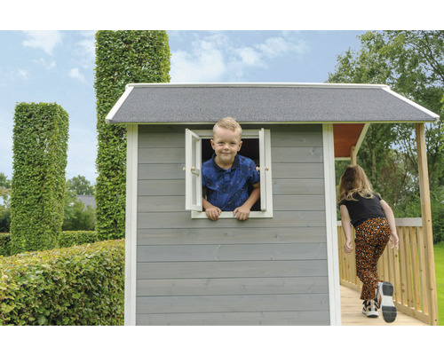 Kinderspielhaus mit Kind am Fenster und Mädchen auf der Veranda im Garten