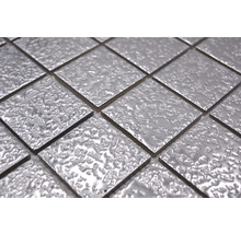 Nahaufnahme von quadratischen, silberfarbenen Mosaikfliesen mit unebener Oberfläche.