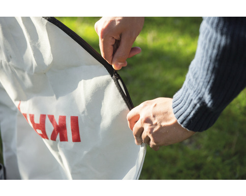 Person verschließt einen Laubsack mit Reißverschluss.