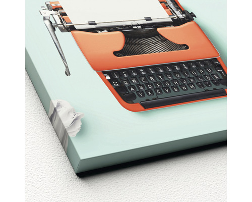 Dekobild einer orangefarbenen Schreibmaschine mit Papier und Papierknüll