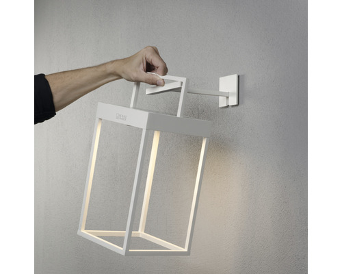 Hand hält weiße Wandleuchte im Laternenstil