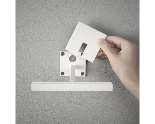 Person befestigt einen Sichtschutz an einer Gardinenstange an der Wand.