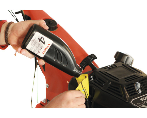 Eine Person füllt Öl aus einer Flasche in einen Motor.