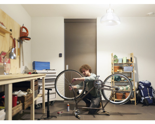 Mann repariert Fahrrad in einer Werkstatt mit Werkbank und Regal