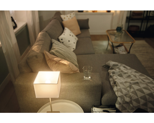 Wohnzimmer mit grauer Eckcouch, Kissen, Tischlampe und Beistelltisch