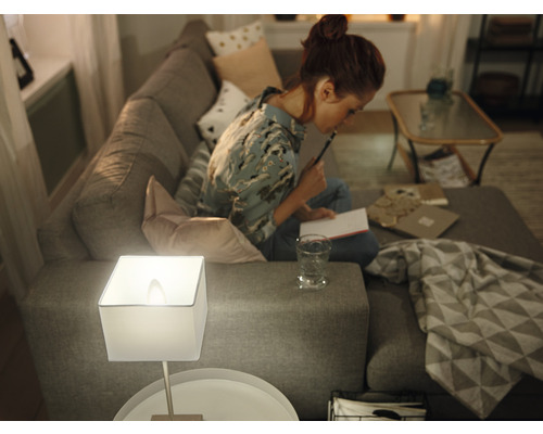 Wohnzimmer mit Lampe auf Beistelltisch und Frau auf Sofa