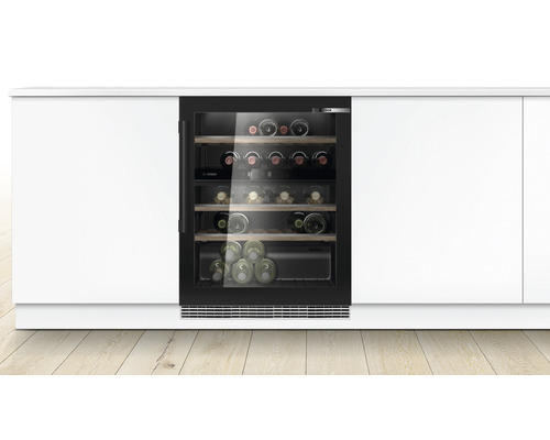 Eingebauter Weinkühlschrank mit Glasfront und mehreren Weinregalen zwischen weißen Schränken.