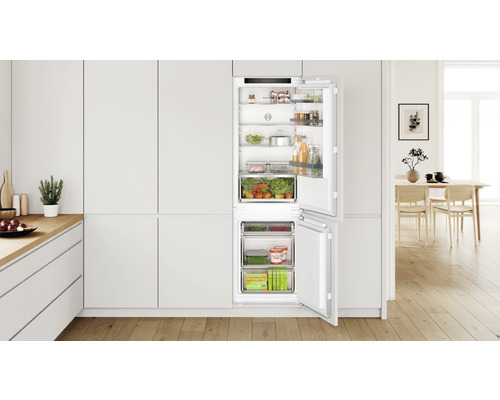 Integrierter Kühlschrank mit geöffneter Tür in einer hellen Küche, gefüllt mit Lebensmitteln.