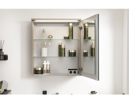 Geöffneter Spiegelschrank mit Glasböden und diversen Badartikeln.