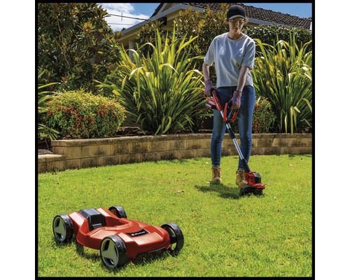 Frau arbeitet im Garten mit Rasentrimmer und Mähroboter.