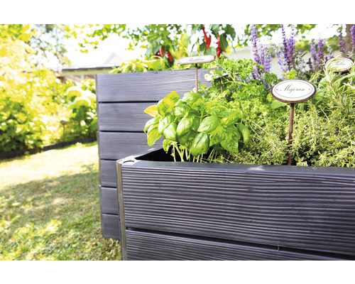 Hochbeete aus Holz mit Kräutern und Pflanzen im Garten.