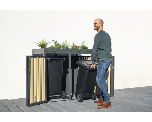 Mülltonnenbox mit Bepflanzung und Mann mit Mülltonne