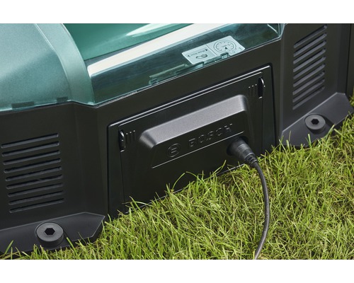 Detailansicht eines Rasenmähroboters beim Ladevorgang mit eingestecktem Ladekabel und Bosch Logo