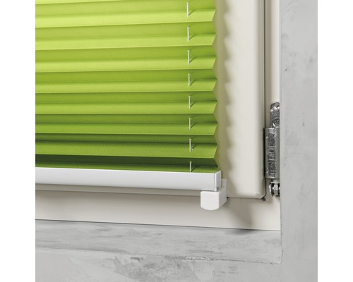 Detailansicht einer grünen Fensterplisseeanlage in einem Fensterrahmen.