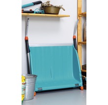 Eine blaue Schneeschaufel steht in einem Lagerraum an der Wand.