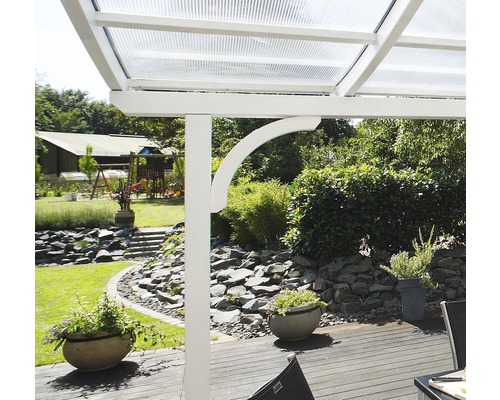 Detailansicht einer Terrassenüberdachung mit weißem Rahmen und transparentem Dach in einem Garten.