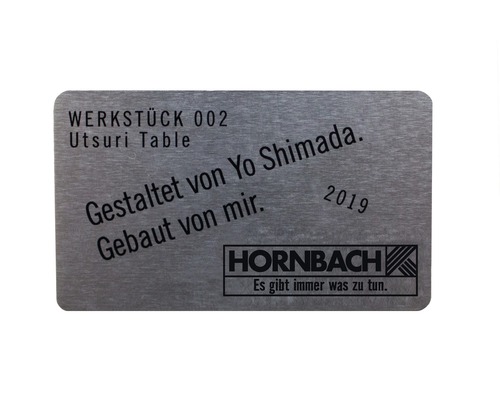 Metallschild mit der Aufschrift Werkstück 002 Utsuri Table, gestaltet und gebaut von Yo Shimada, 2019, Hornbach Logo