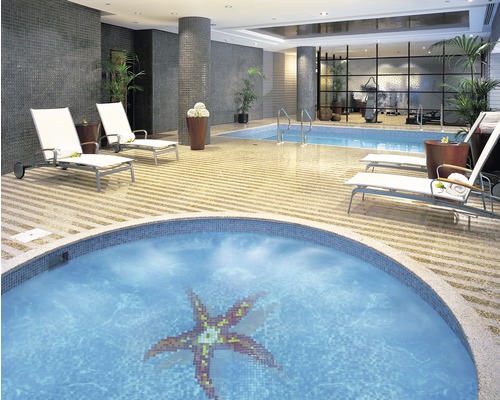 Innenansicht eines hellen Wellnessbereichs mit Whirlpool, Pool und Liegestühlen