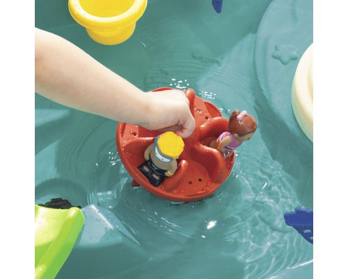 Kind spielt mit einer Wassermühle und Spielfiguren im Planschbecken