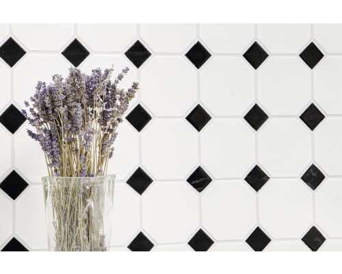 Dekorative Fliesenwand mit geometrischem Muster und einem Strauß Lavendel in einem Glas.