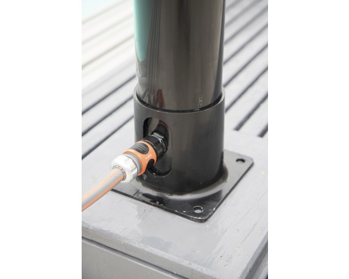 Wasseranschluss an einer Sonnenschirmbasis mit einem Gartenschlauch verbunden.