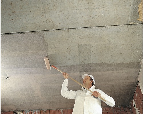 Ein Mann streicht eine Zimmerdecke mit einer Farbwalze.