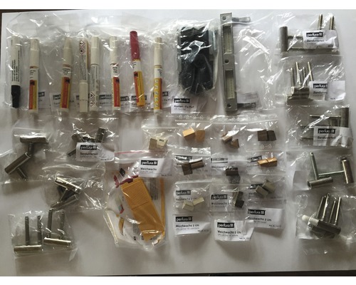 Sortiment an Reparaturmaterialien, darunter Lackstifte, Beschläge und Weichwachs in Kunststoffverpackungen.