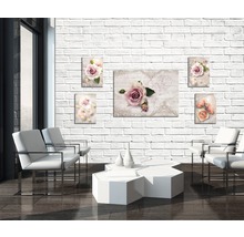 Wohnzimmer mit weißen Sesseln, Tisch und Wandbildern mit Rosenmotiven an einer Ziegelwand