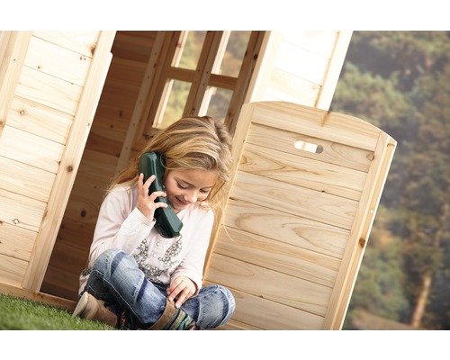 Mädchen sitzt mit Spielzeugtelefon in einem Holzspielhaus