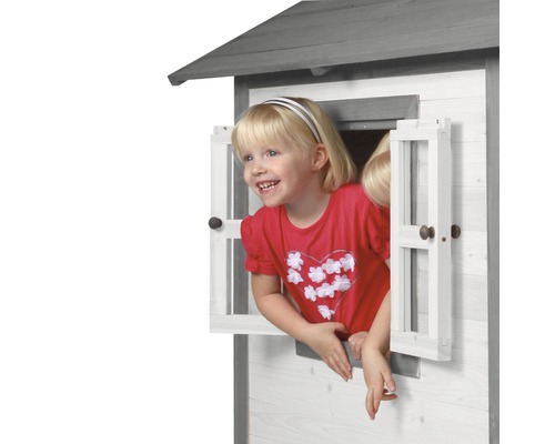 Mädchen schaut aus dem Fenster eines Spielhauses aus Holz