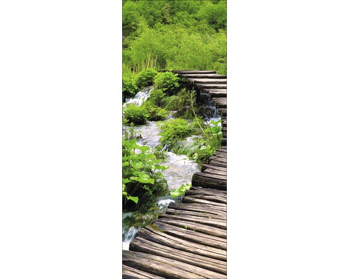 Holzsteg über einen Bach in einer grünen Landschaft