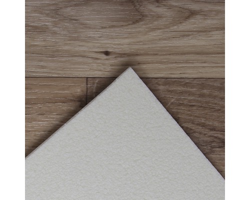 Detailansicht einer weißen Vinylfliese auf einem Holzboden.