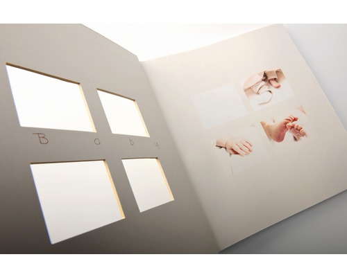 Offenes Babyfotoalbum mit Aussparungen und Fotos