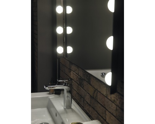 Badezimmerwaschbecken mit Armatur und beleuchtetem Spiegel im Backsteindesign