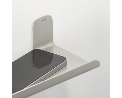 Tiger Logo. Telefontablett aus Metall an der Wand mit Mobiltelefon.