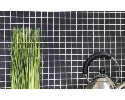 Dekorative grüne Halme und ein Teekessel vor einer Wand mit Mosaikfliesen