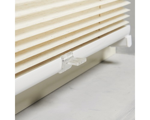 Nahaufnahme einer beigen Plissee-Jalousie mit weißer Halterung zur Fensterdekoration.