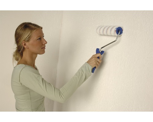 Frau streicht Wand mit Farbroller