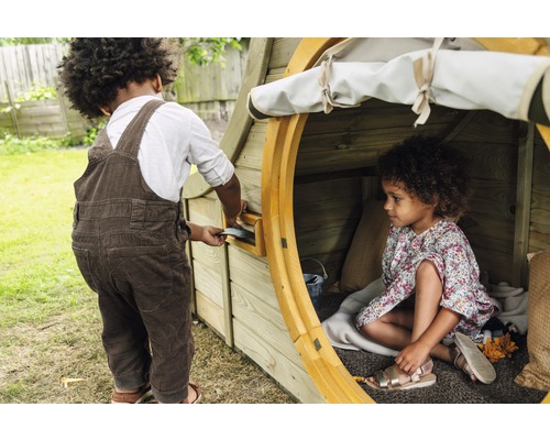 Kinder spielen in einem hölzernen Spielhaus mit Briefkasten im Garten.