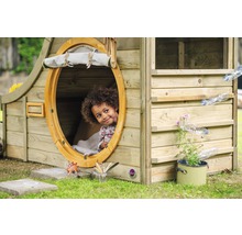 Ein Kind schaut aus einem runden Fenster eines Holzspielhauses mit Wasserspiel.