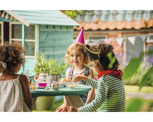 Kinder beim Spielen im Garten mit Spielhaus und Picknicktisch