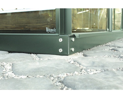 Detailansicht eines Gewächshaus-Fundaments mit Schrauben auf Pflastersteinen