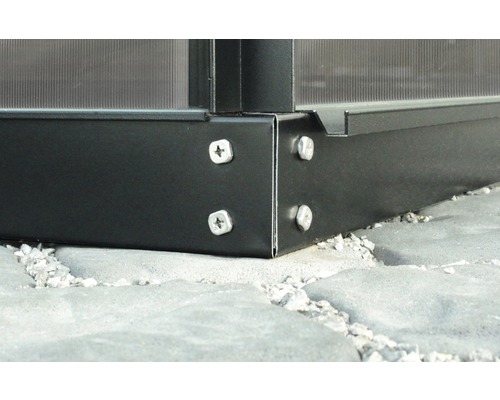 Detailansicht einer Gewächshauskonstruktion aus Metall mit Schrauben auf einem Steinboden.