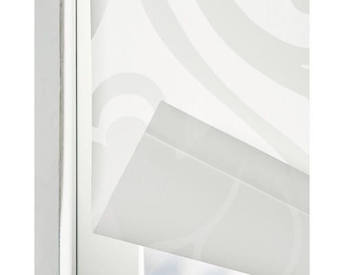Detailaufnahme eines weißen Rollos mit Muster im Fensterrahmen
