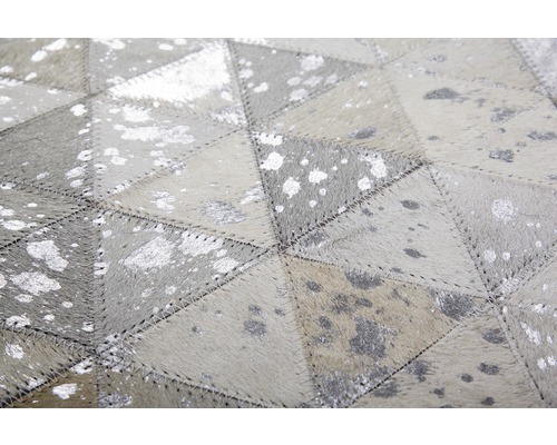 Nahaufnahme eines Teppichs aus Lederstücken mit geometrischem Muster und silbernen Akzenten.