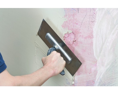 Handwerker glättet Spachtelmasse mit einer Glättkelle an einer Wand.