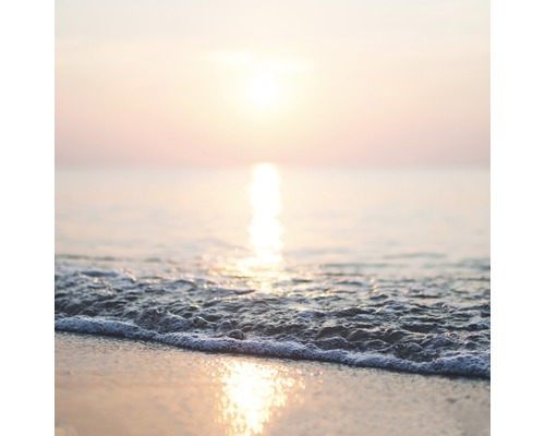 Sonnenaufgang über dem Meer mit Wellen am Strand