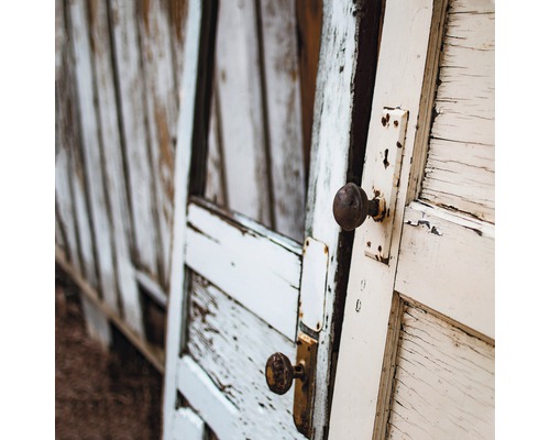 Abgenutzte Holztür mit runden Türknöpfen und abblätternder Farbe