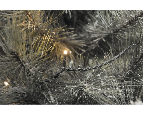 Nahaufnahme einer beleuchteten, künstlichen Tannengirlande mit Schnee